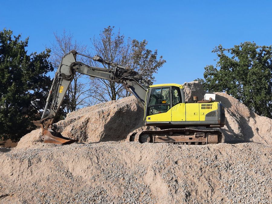 An excavator moving earth on a rural site